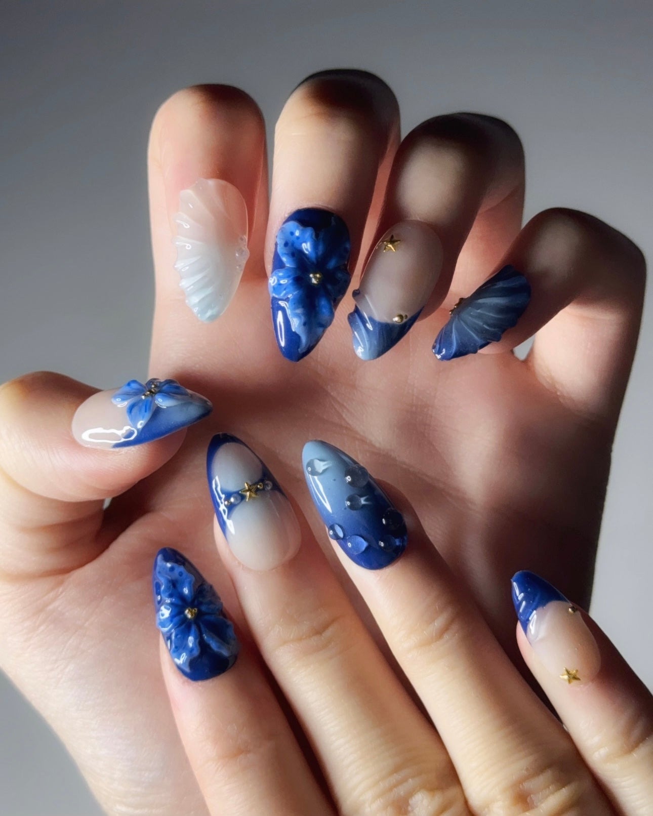 Hand with blue floral nail art on a neutral background