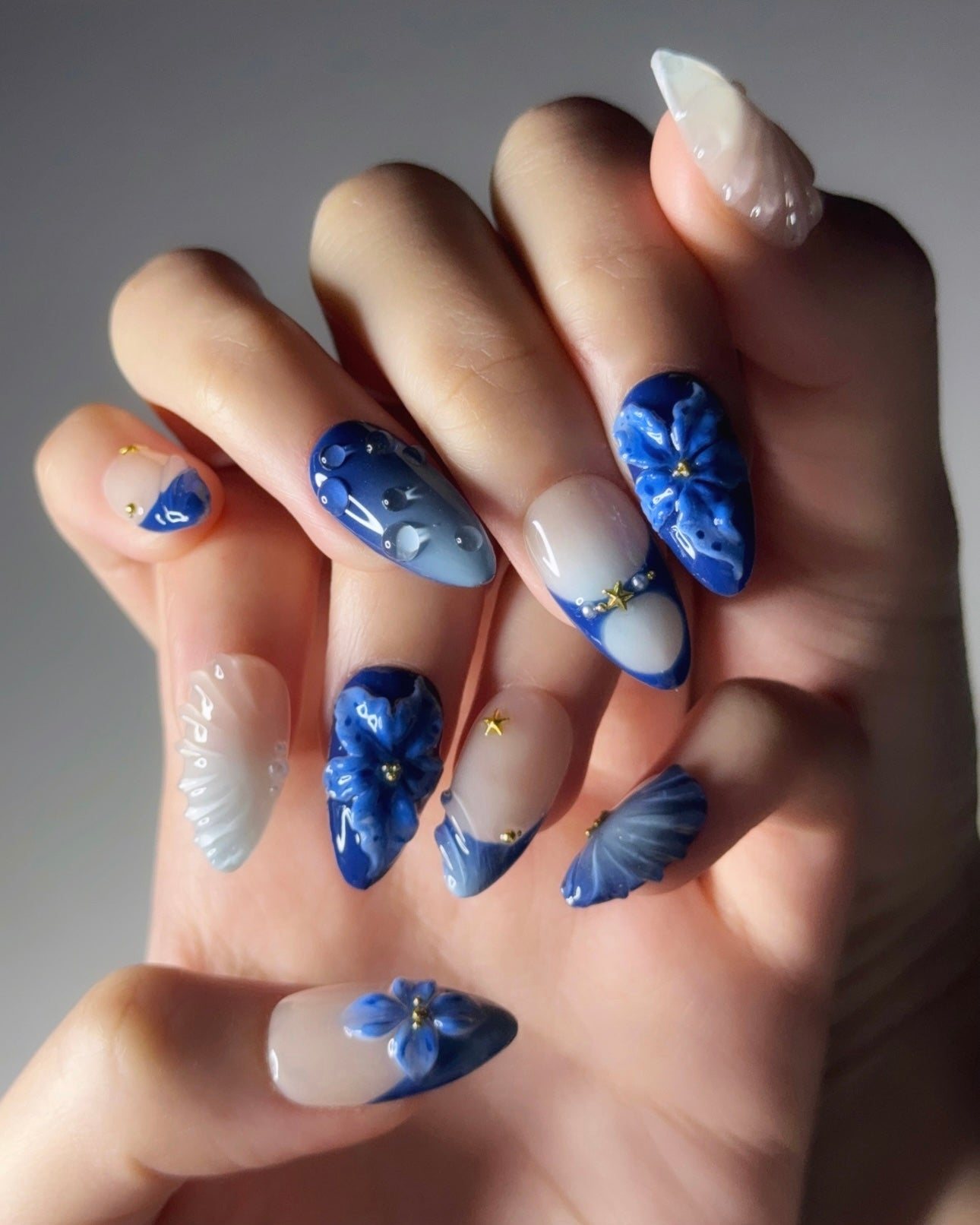 Hand with blue floral nail art on a neutral background