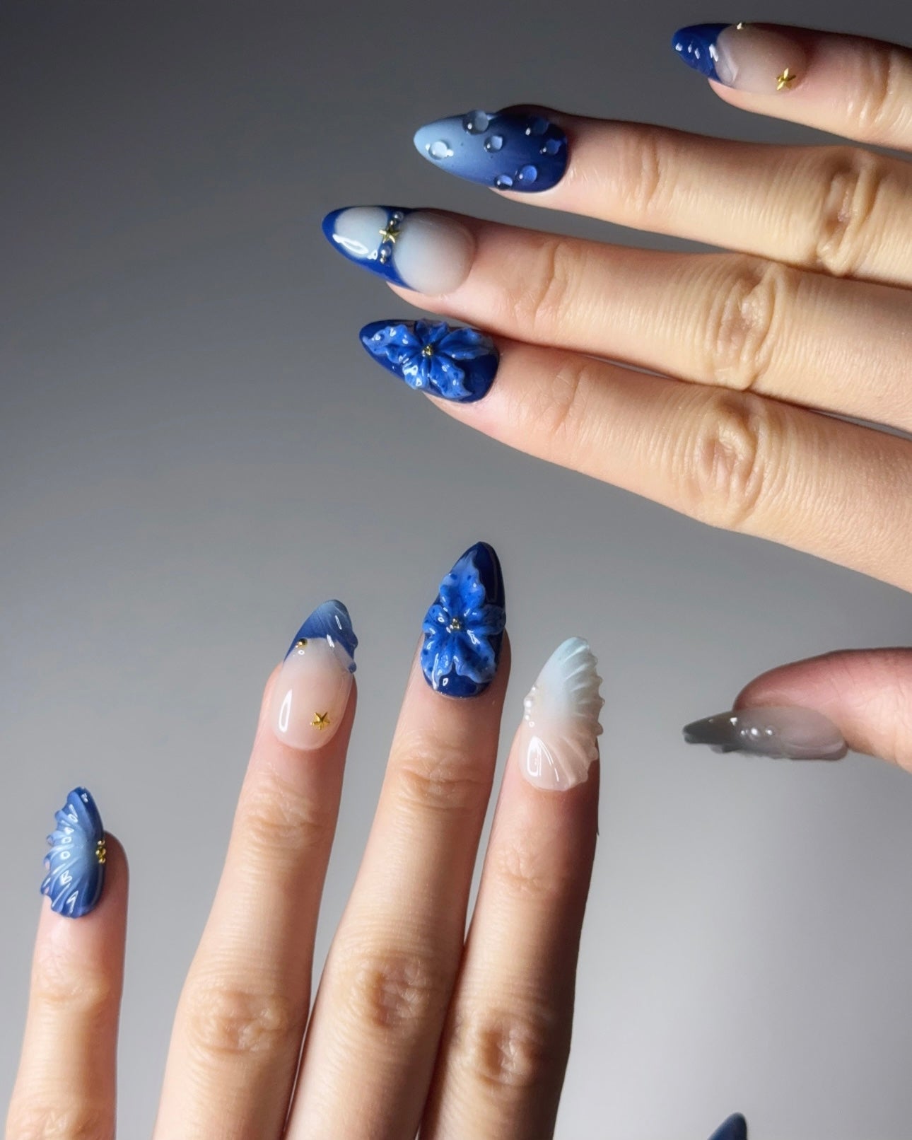 Close-up of hands with blue nail art on a gray background