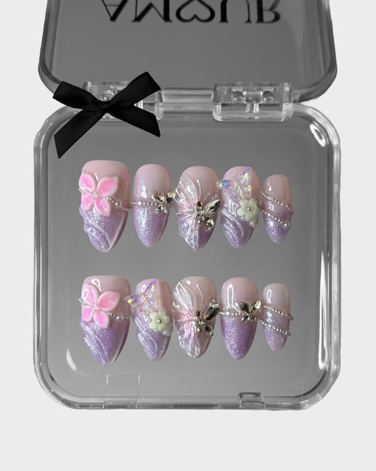 Decorative false nails with butterfly designs in a clear box with a black bow.