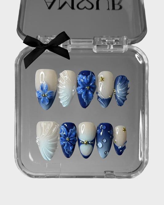 Set of blue and white nail art designs in a clear case with a black bow.
